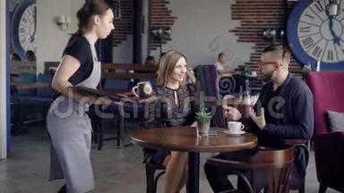 服务员送订<strong>单</strong>。 女服务员为坐在咖啡馆里的年轻夫妇<strong>点餐</strong>。